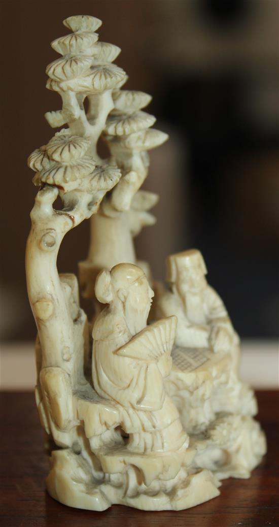 A Chinese ivory group of scholars playing weiqi beneath a pine tree, 19th century, 8.7cm, wood stand, slight repair